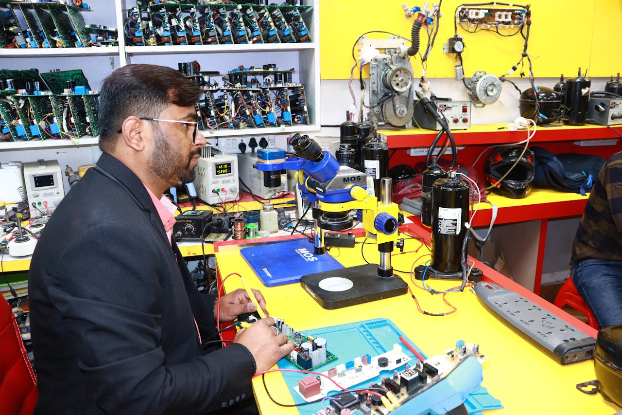mobile-01 A man in Delhi working in an electronics lab with tools and components.