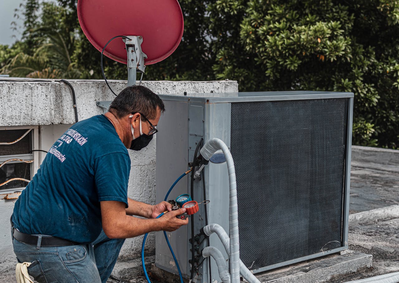 creative-03 Technician repairing an air conditioner unit outdoors, wearing a facemask and using a manifold gauge.