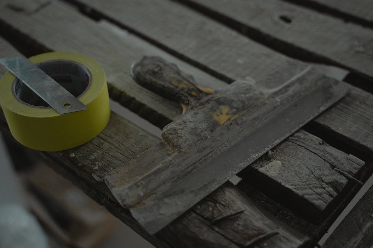 creative-01 Close-up of a spatula and duct tape on an aged wooden surface. Perfect for DIY and renovation themes.